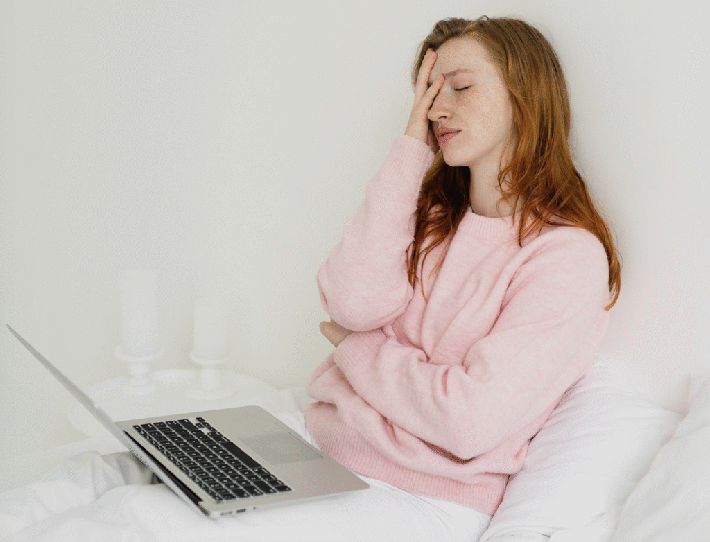 A woman does a face palm while sitting at her computer.